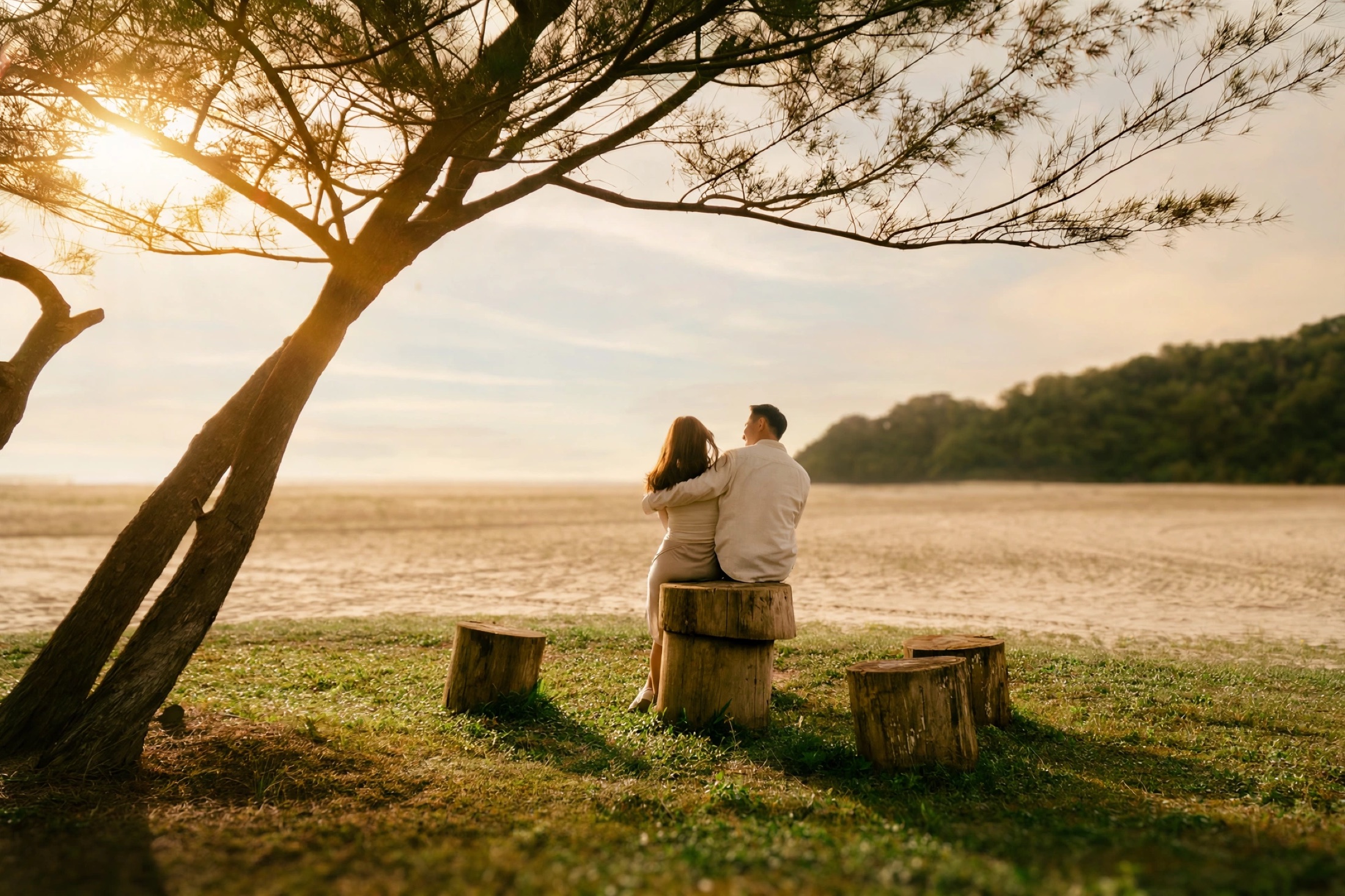 Ian and Phylicia sitting together beneath a sunset tree by the beach