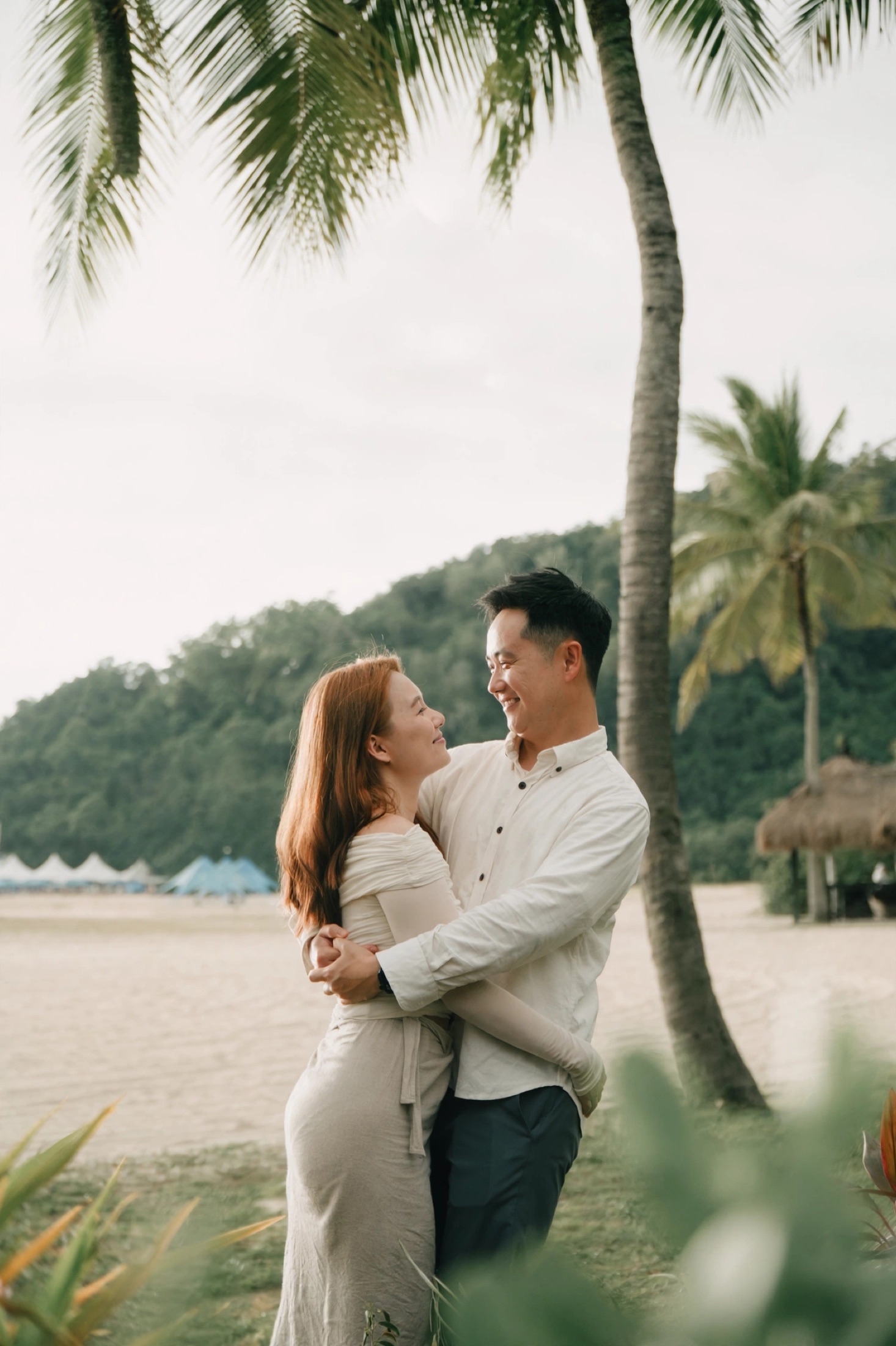 Ian and Phylicia embracing beneath palm trees